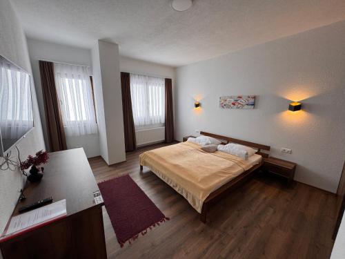 a bedroom with a bed and two windows at Casa Leone Hotel&Restaurant in Popova Shapka