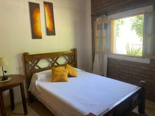 ein Schlafzimmer mit einem Bett mit gelben Kissen und einem Fenster in der Unterkunft El cordobes in Albardón