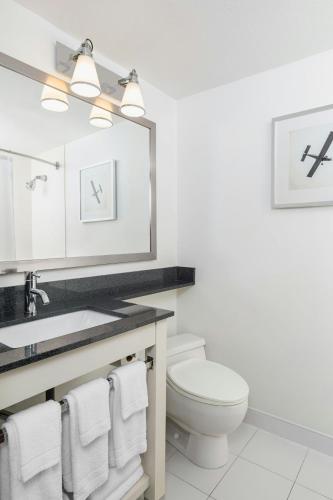 a bathroom with a toilet and a sink and a mirror at Four Points by Sheraton Chicago O'Hare in Schiller Park