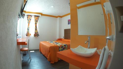 a bedroom with a bed and a sink and a mirror at Hotel Yekkan in Huauchinango