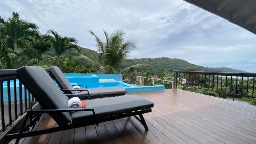 a deck with two lounge chairs and a pool at Stephna Residence in Anse Boileau