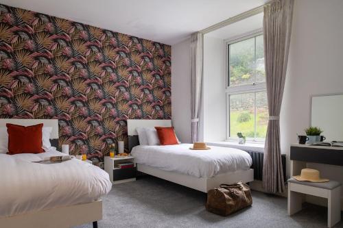 a bedroom with two beds and a large window at Eryri Snowdonia Premier Family Retreat with Hot Tub and Fire Pit in Dolgellau