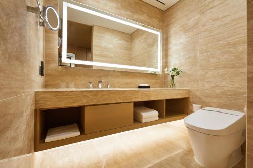 a bathroom with a sink and a toilet and a mirror at Marriott Jeju Shinhwa World Hotel in Seogwipo