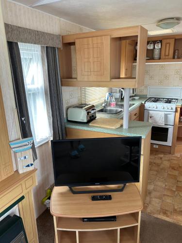 a kitchen with a tv on a wooden table at 2-Bed Ingoldmells Caravan - Pet Friendly & Decking in Skegness