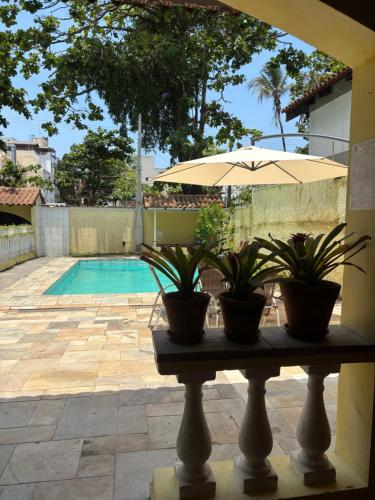 a table with two potted plants and an umbrella at Pousada As Ondas in Guarujá
