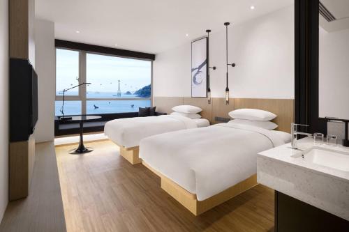 two beds in a room with a view of the ocean at Fairfield by Marriott Busan Songdo Beach in Busan