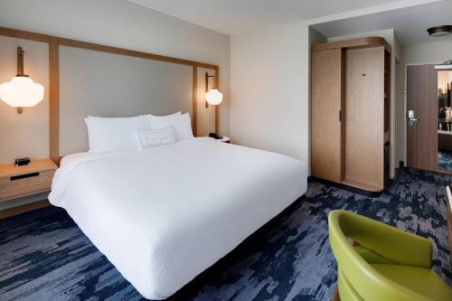 a bedroom with a large white bed and a green chair at Fairfield Inn & Suites by Marriott Tampa Wesley Chapel in Wesley Chapel