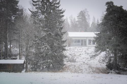 a snow covered yard with a house and trees at Villa Bessberget in Edsbyn