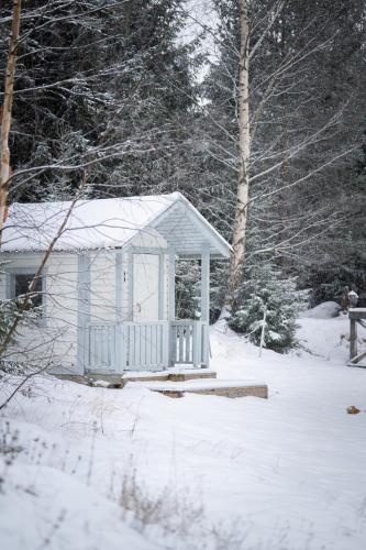 a small white shed in the snow with trees at Villa Bessberget in Edsbyn