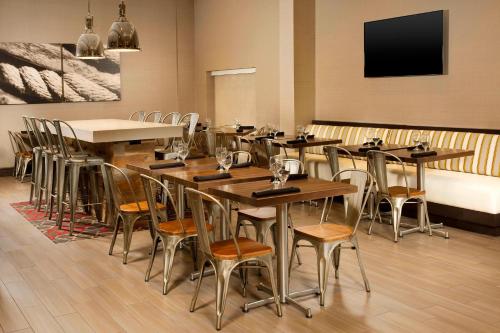 a restaurant with wooden tables and chairs and a flat screen tv at Four Points by Sheraton Jacksonville Beachfront in Jacksonville Beach