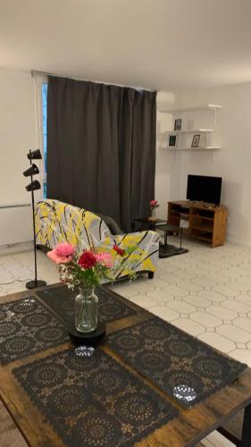 un salon avec un canapé et une table avec des fleurs dans l'établissement Le Calme, à Sèvres