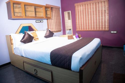 Cama grande en habitación con paredes moradas en The Ecostay Villa, en Pondicherry