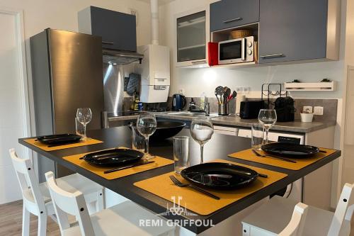 une cuisine avec une table avec des assiettes et des verres à vin dans l'établissement Les 4 éléments apartment 4 with balcony elevator and private parking, à Honfleur