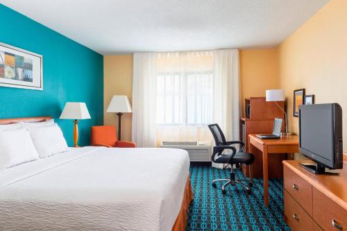 a hotel room with a bed and a desk and a television at Fairfield Inn Muncie in Muncie
