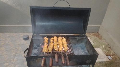 a grill with several skewers of food on it at NHC full cottage in Nandi