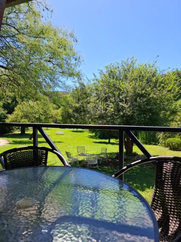 a glass table on a balcony with a view of a park at Le Bel-Edén in Villa General Belgrano