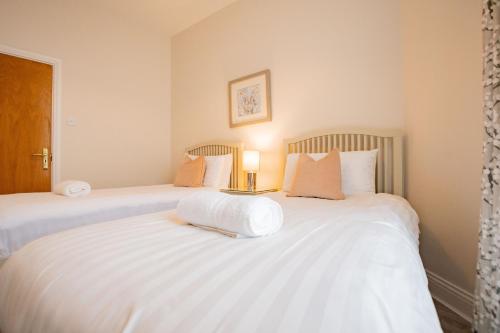 two beds in a bedroom with a lamp on a table at Long Walk Gem in Galway