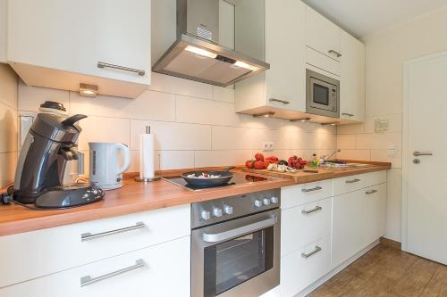 a kitchen with white cabinets and a counter top at Broderhus Bude in Sankt Peter-Ording