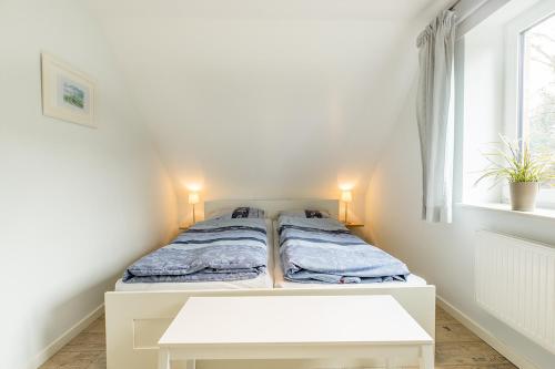 a small bedroom with a bed and a table at Broderhus Bude in Sankt Peter-Ording