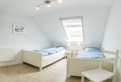 a bedroom with two beds and a window at Broderhus Bude in Sankt Peter-Ording