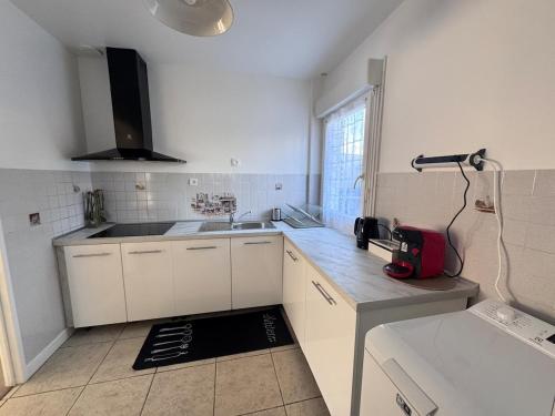 une petite cuisine avec des armoires blanches et un évier dans l'établissement Séjour détente et confort au calme d une impasse, à Garges-lès-Gonesse