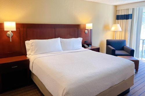a hotel room with a large bed and a blue chair at Four Points by Sheraton San Rafael Marin County in San Rafael