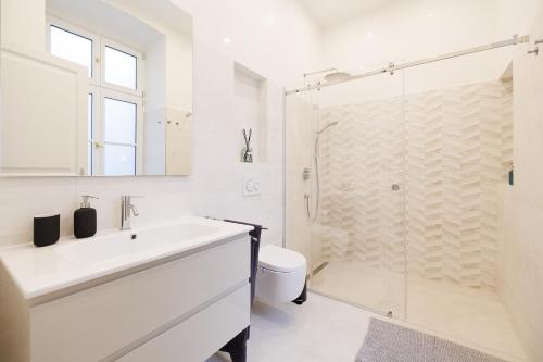 Un baño blanco con lavabo y ducha en Ultra Spacious 3-Bedroom 3-Bath Steps from Vienna's Historic Heart, en Viena