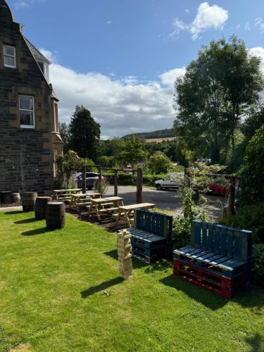 a row of benches in the grass next to a house at The Retreat Hotel in Strathpeffer