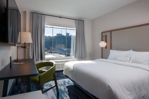 ピッツバーグにあるFairfield by Marriott Pittsburgh Downtownのベッド、デスク、窓が備わるホテルルームです。