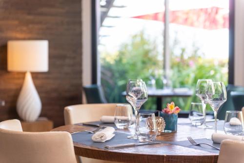 a table in a restaurant with wine glasses on it at Hôtel Traiteur Les Ormes, The Originals Relais in Barneville-Carteret