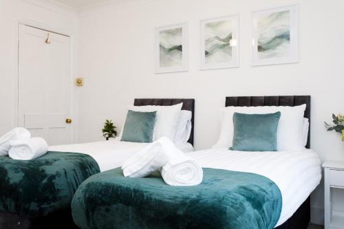 two beds with green ottomans in a bedroom at Cosy House - Stanstead Airport in Bishops Stortford