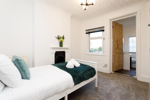 a white bedroom with a bed and a fireplace at Cosy House - Stanstead Airport in Bishops Stortford
