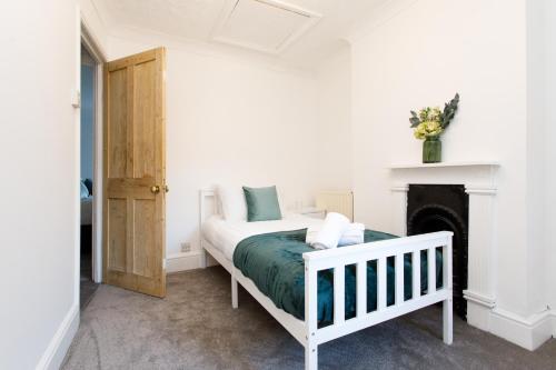 a white bedroom with a bed and a fireplace at Cosy House - Stanstead Airport in Bishops Stortford