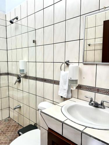 a bathroom with a sink and a toilet and a mirror at Hotel Arenal Rabfer in Fortuna