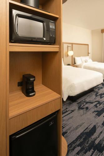 a hotel room with a television and a bedroom at Fairfield Inn & Suites Vero Beach in Vero Beach