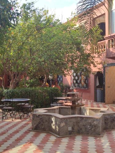 a fountain in a courtyard with tables and benches at Riad les jardins Mabrouk in Taroudant