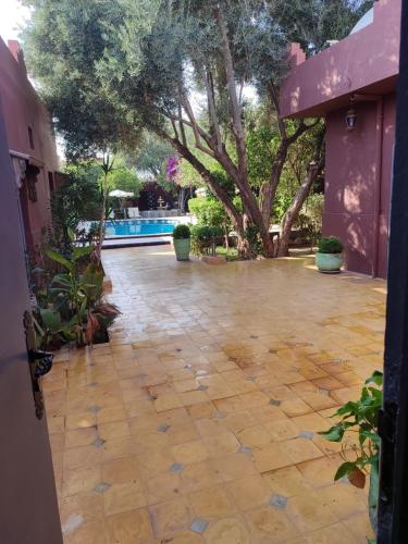 a stone courtyard with a tree and a swimming pool at Riad les jardins Mabrouk in Taroudant