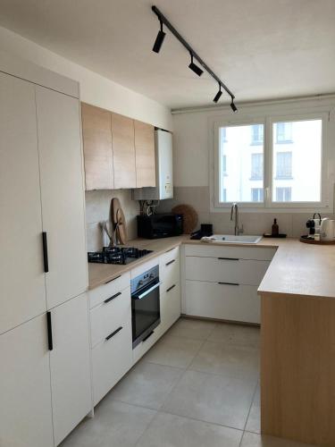 a white kitchen with white cabinets and a sink at 63m2 Lumineux proche Stang Alar in Brest
