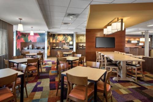 a dining room with tables and chairs and a tv at Fairfield Inn & Suites by Marriott New Castle in New Castle