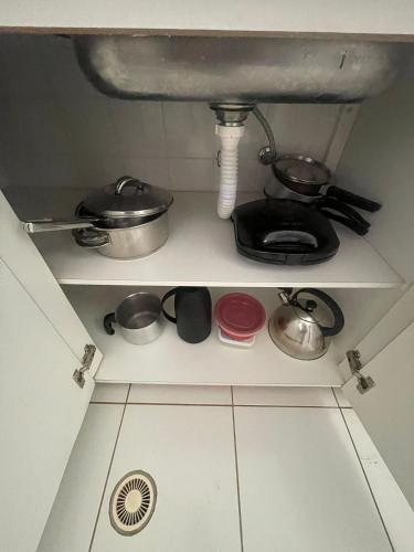 a kitchen shelf with pots and pans and a sink at Edifício Belluno in Ribeirão Preto