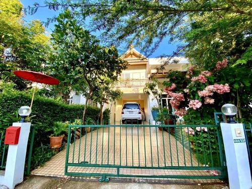 a gate to a house with a car in the driveway at Modern Thai Style Garden Home in Chiang Mai