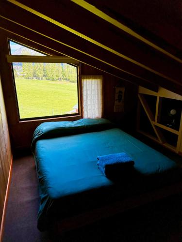 a bed in a room with a window at Hostal Las Natalias in Futaleufú