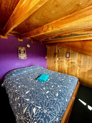a bedroom with a bed with a blue and white comforter at Hostal Las Natalias in Futaleufú