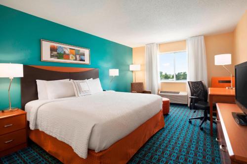 a hotel room with a bed and a desk and a television at Fairfield Inn & Suites Lansing West in Delta Center Township