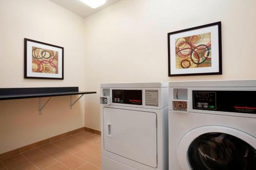 a washing machine in a laundry room with two pictures at Fairfield Inn & Suites Lansing West in Delta Center Township