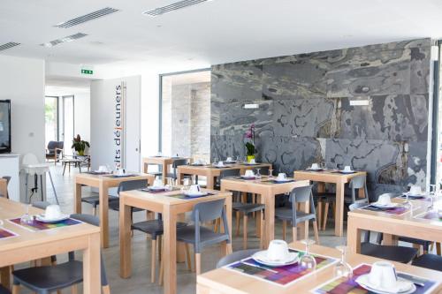 un restaurant avec des tables et des chaises en bois et un mur en pierre dans l'établissement Hotel Restaurant Santiago, à Hendaye