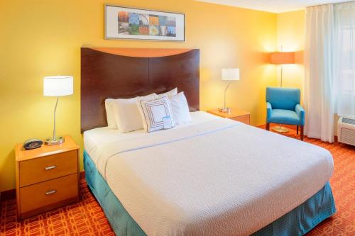 a bedroom with a large bed and a blue chair at Fairfield Inn Joplin in Joplin