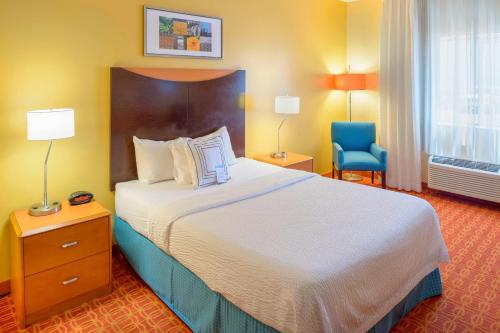 a hotel room with a bed and a blue chair at Fairfield Inn Joplin in Joplin
