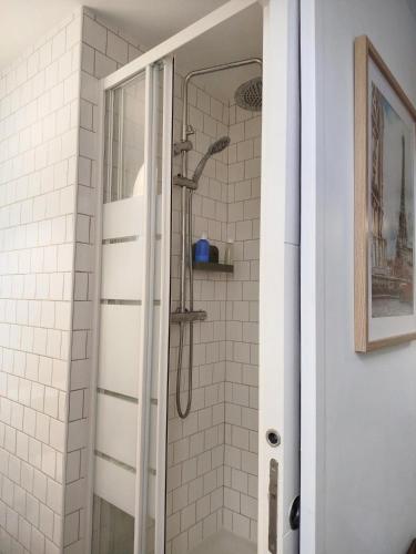 une douche dans une salle de bain avec du carrelage blanc dans l'établissement Le Vinted Chic - 15 min des Champs-Elysées, à Saint-Ouen