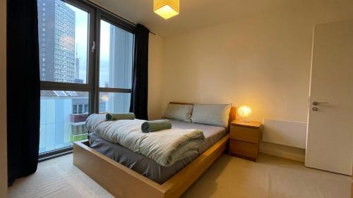 a bedroom with a bed and a large window at Stratford 2 bedroom Apartment with 2 Bathrooms & Great Links in London